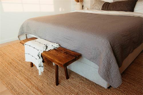 Minimalist bedroom with gray bed, wooden bench, and jute rug