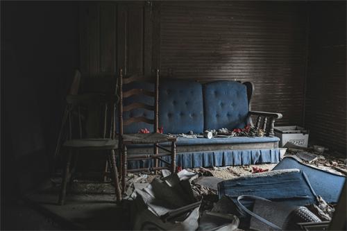 Old abandoned blue sofa in a derelict room