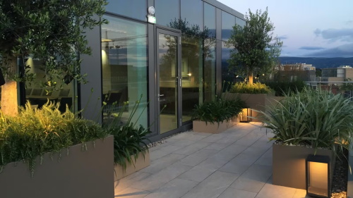 Modern rooftop terrace with planters and evening lighting