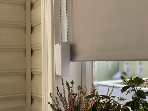 A motorized smart window blind controller mounted on a window frame